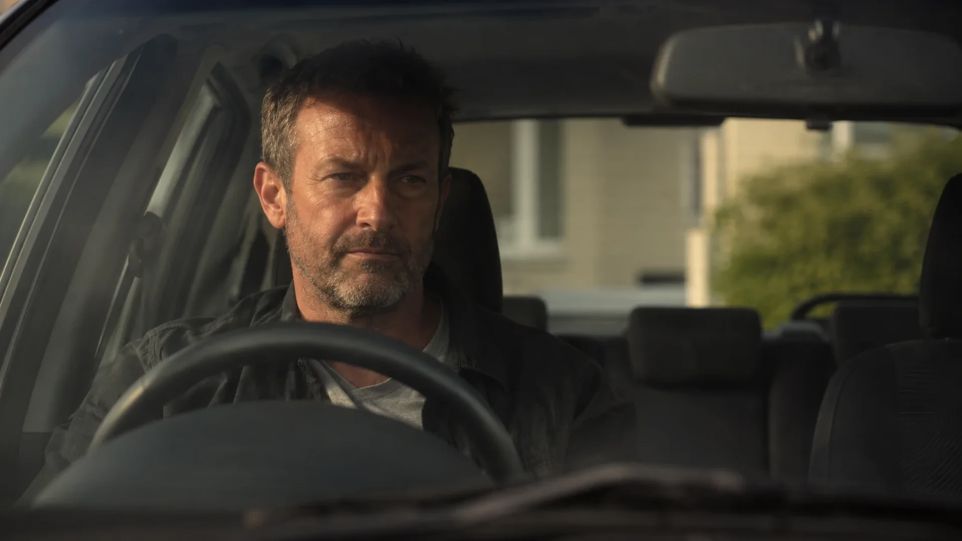 Man in a car in a driveway, engine off, not ready to go inside